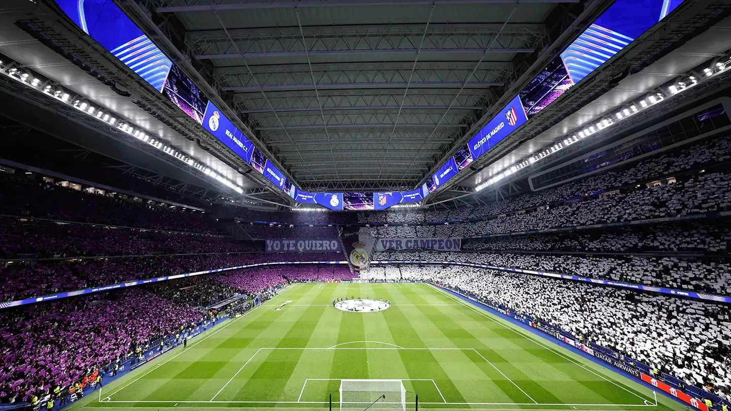 Las gradas escalonadas de un gran estadio de fútbol al atardecer.